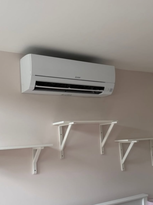 ETS Envirotemp Services - Mitsubishi wall-mounted indoor air conditioning unit above three white shelves on a pale wall; air conditioning installations in Kent, Essex and London